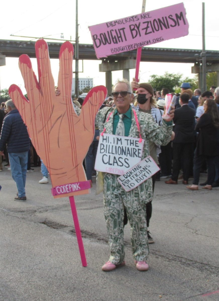 A protester outside of the convention poses with signs that read: “Hi, I’m the Billionaire Class, Looking 4 Politicians to Buy!!” (Forebaugh/LION).

