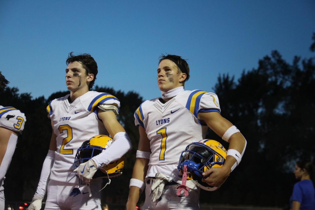 Left to Right: Travis Stamm ‘25 and Mack Long ‘25 watch the Hinsdale Central band play the national anthem (Waliewski/LION).
