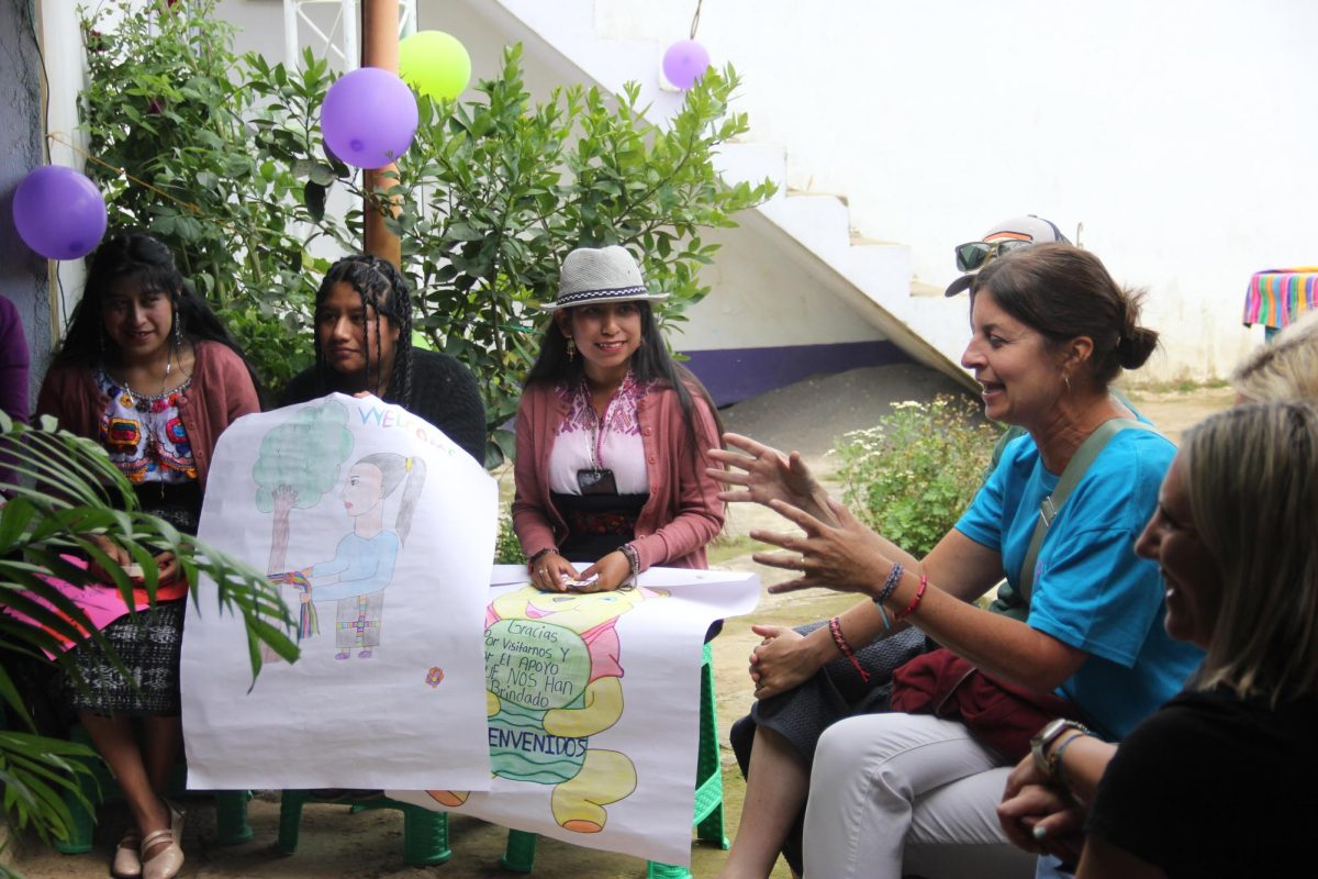 Lisa Plichta and other trip attendees talk with Pulsera Project artisans outside (courtesy of Crane).