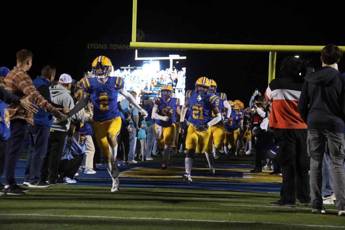 Left to Right: Captains Travis Stamm ‘25, Cooper Komsthoeft ‘25, and Shane Harris ‘25 break the tunnel on Senior Night before the Oct. 25 game against Proviso East. 

