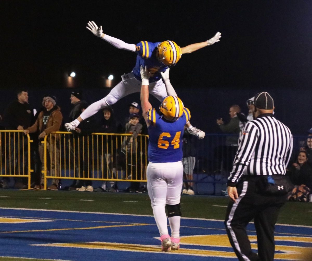 Cooper Komstoepft ‘25 lifts up Travis Stamm ‘25 in celebration after Stamm’s touchdown against Downers Grove South on Nov. 8 (Brooks/LION).
