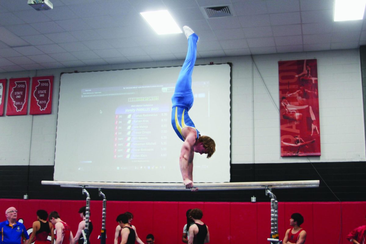 Sean McCabe ‘25 does handstand on the parallel bars at a meet against Hinsdale Central on March 7 (Simmons/LION).
